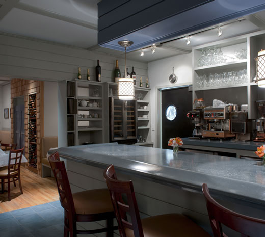 bar counter corner with hanging cylindrical light fixture and seating